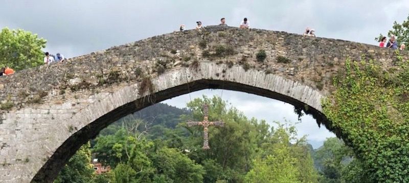 Una réplica de la Cruz de la Victoria pende del arco principal del puente